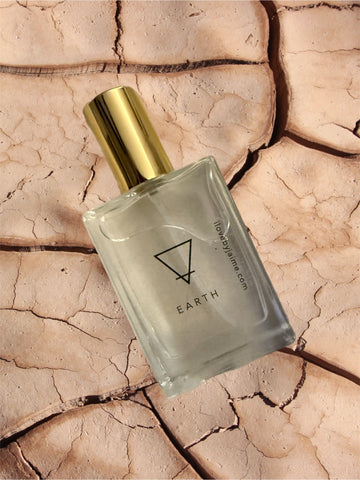 Perfume bottle labeled 'Earth' on a textured beige background
